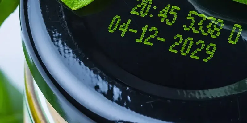 Continuous inkjet printer coding a date onto food packaging as it passes on the line